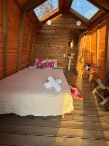 a bed in a wooden cabin with two towels at La Nebulosa Glamping in Vergara