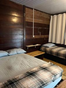 a bedroom with two beds and wooden walls at Chalé Mar Aberto in Atins