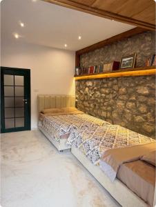 a bedroom with two beds and a stone wall at Skadar Lake Hideaway in Karuč