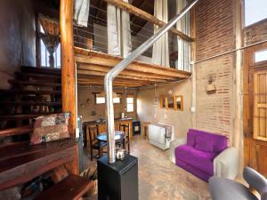 a living room with a purple couch and a table at Arrullo del viento in Villa Yacanto