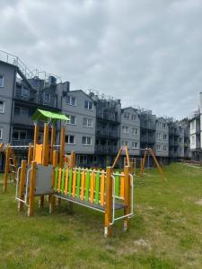 a playground in a park with buildings in the background at Apartamenty Modrzewiowa Enklawa in Debina
