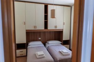 two beds in a small room with white cabinets at Casa Giordana in Torri del Benaco +38 photos
