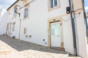 a white building with a door on a street at Bicas Velhas Studio in Loulé +27 photos