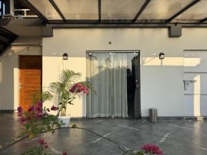 a pivot door in a white building with flowers at Terrace By Opal in Barābhīta