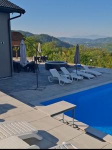 a pool with lounge chairs and umbrellas next to at Villa Aqua Tuzla in Drenovik