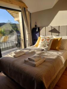 a bed with towels on it with a large window at Apartamenty Etno Pieniny in Jaworki