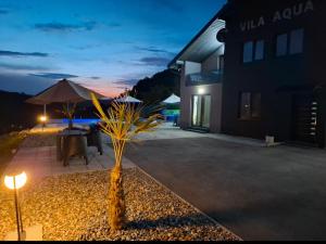 a patio with a table and an umbrella at night at Villa Aqua Tuzla in Drenovik