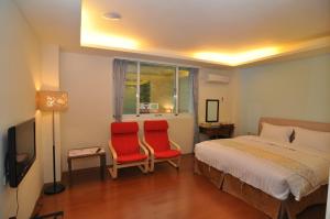 a bedroom with two red chairs and a bed at Cheng-Ping Hot Spring Inn in Wenquan