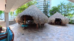 a patio with tables and chairs and straw umbrellas at Hotel Bahia Cartagena in Cartagena de Indias