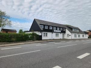a white house with a black roof on the side of a road at Ferielejlighed ved Vilsted Sø in Løgstør