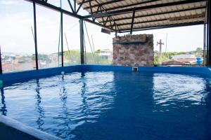 an indoor swimming pool with blue water and windows at Hotel Perla Azul Girardot in Girardot