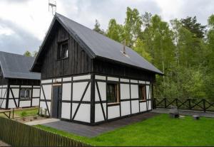 a black and white house with a grass yard at Domek Na Gwizdówce nr52 in Załakowo
