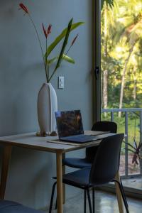 a laptop on a table with a vase with a plant at Elegant and Stylish - Riverside Tiny House Apartment in El Valle