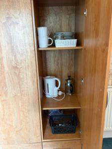 a cupboard with two mugs and other items in it at Kinkell House in Inverness