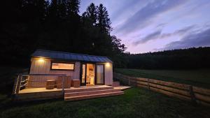 a tiny house with a deck in a field at Glamping Šumava in Hartmanice