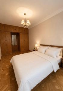 a large white bed in a bedroom with a chandelier at Nice Apartment in the City Center in Yerevan
