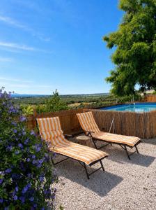 two chairs sitting next to a fence with a swimming pool at Monte da Rocha-Mãe in Barro Branco