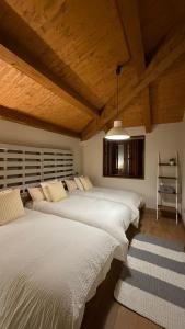 two beds in a room with wooden ceilings at Casa de piedra en el valle a 20 minutos de Ribadeo y Playa de las Catedrales in Salcido