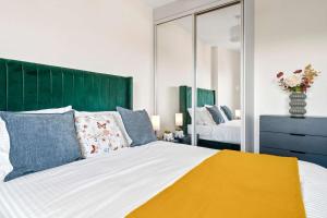 a bedroom with a large bed and a mirror at Modern 2 Bedroom Flat with FREE Parking, Close to Heathrow and Thorpe Park in Staines