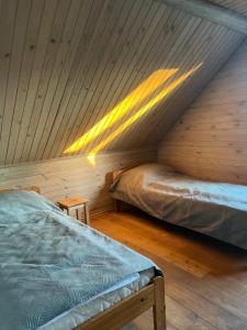 a attic bedroom with two beds and a wooden ceiling at Pas Šerną in Macionys