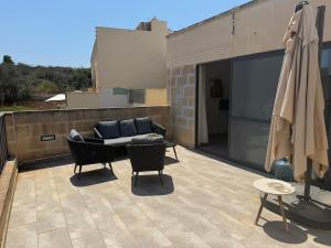 a patio with a couch and chairs on a roof at Sea Views Penthouse Apartment in Xagħra