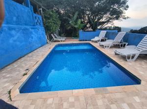 a swimming pool with chairs and a blue wall at CHÁCARA dos CHEIROS in Atibaia