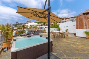a pool with an umbrella and a table and chairs at Raices Nomadas Boutique Hotel Vallarta in Puerto Vallarta