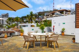 a patio with a table and chairs on a roof at Raices Nomadas Boutique Hotel Vallarta in Puerto Vallarta