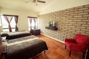a bedroom with two beds and a chair and a brick wall at La Ilusión Hotel Campestre y Balneario in Parras de la Fuente