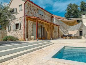 a stone house with a swimming pool in front of it at Dolce Terra in Stari Grad