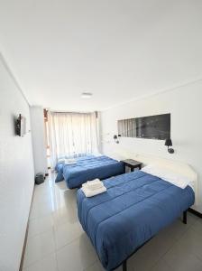 a hotel room with two beds and a tv at Alojamiento La Ballena in Santoña