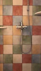 a shower with a hose on a tiled wall at Vrakades - Guest House in Kouniádhoi