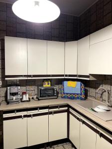 a kitchen with white cabinets and a large light fixture at Casa Sciavè - Paradise in Sciacca in Sciacca