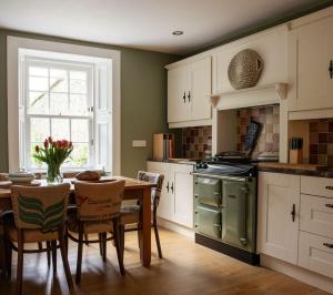 a kitchen with a table and chairs and a kitchen with a stove at Newbyth Garden Cottage in East Linton