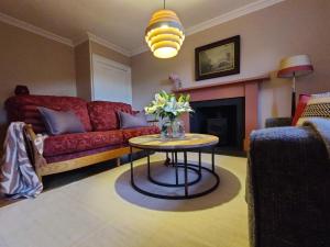 a living room with a couch and a table with flowers on it at Newbyth Garden Cottage in East Linton