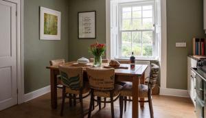 a dining room table with chairs and a vase of flowers at Newbyth Garden Cottage in East Linton +25 photos