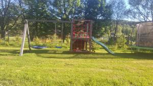 a playground with a slide in the grass at Bliżej Lasu - Rodzinny domek w górach in Stary Gieraltów