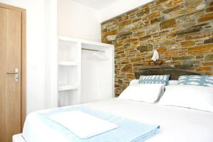 a white bed in a room with a brick wall at Utopia Kythnos Althea in Kithnos +14 photos