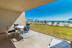 a patio with a table and chairs and a view of the beach at Beach House Condominiums C103 - Beachfront with Pool, Wi-Fi, & Beach Service in Destin