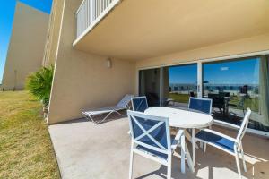 a patio with a table and chairs on a balcony at Beach House Condominiums C103 - Beachfront with Pool, Wi-Fi, & Beach Service in Destin