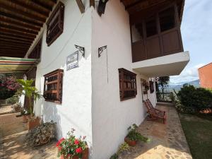 a white building with wooden windows and a bench at Villa Palosanto Campestre in Jericó