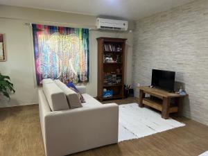a living room with a white couch and a tv at Espaço Aconchego in Pomerode