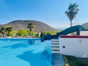 a slide in a swimming pool with a mountain in the background at La Ilusión Hotel Campestre y Balneario in Parras de la Fuente