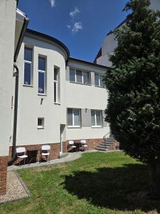 a building with chairs and a tree in front of it at Apartmány Kukučín in Košice