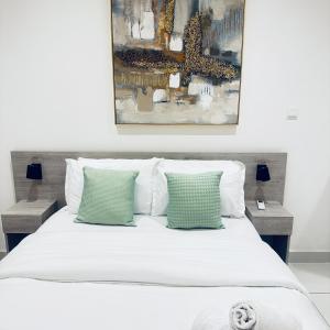 a bedroom with a white bed with two green pillows at Loxwood by Tripview Apartments in Accra +86 photos