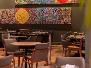 a dining room with tables and chairs and a painting at Novotel Curitiba Batel in Curitiba