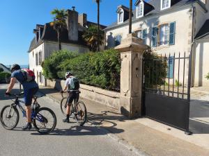 two people riding bikes down a street next to a house at Ty Palms - Maison d'hôtes in Plomodiern