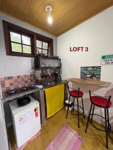 a kitchen with a counter and two red stools at Mi Casa Su Casa Lofts in Abraão