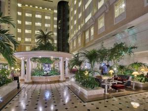 a lobby of a hotel with tables and plants at Rixos President Hotel Astana in Astana