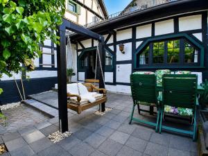 a porch with two green chairs and a swing at Ferien im Kellisch-Haus in Schalkenmehren